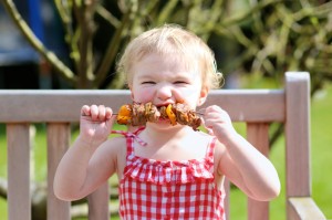 Little girl eating grilled kabob