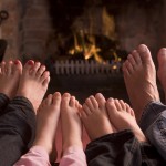a family of bare feet being warmed by a fire