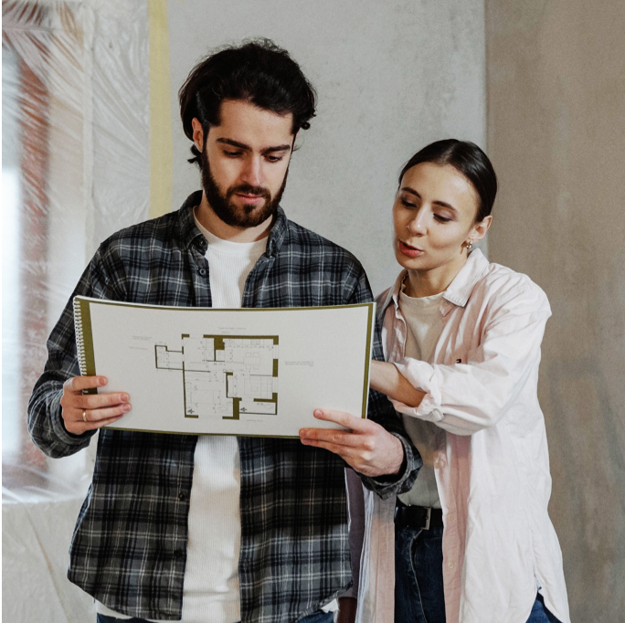 A couple in a construction site looking and house blueprints