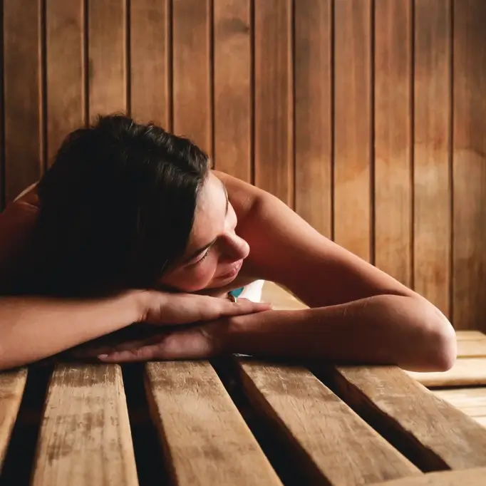 Woman lying on sauna bench